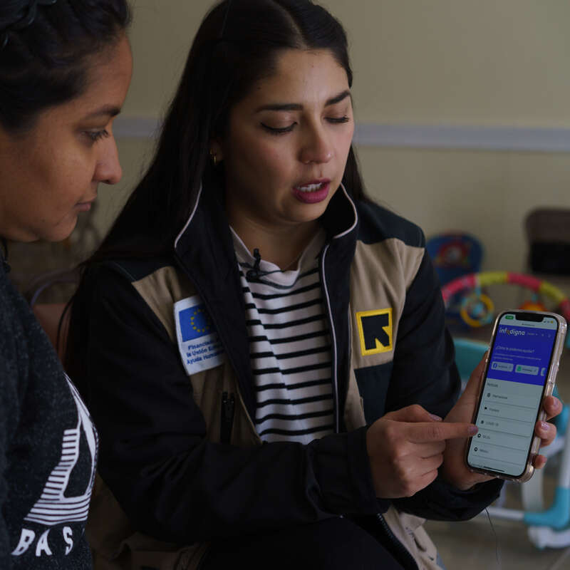 En RESCUE-medarbetare visar en kvinna en app som ger information till personer på flykt.