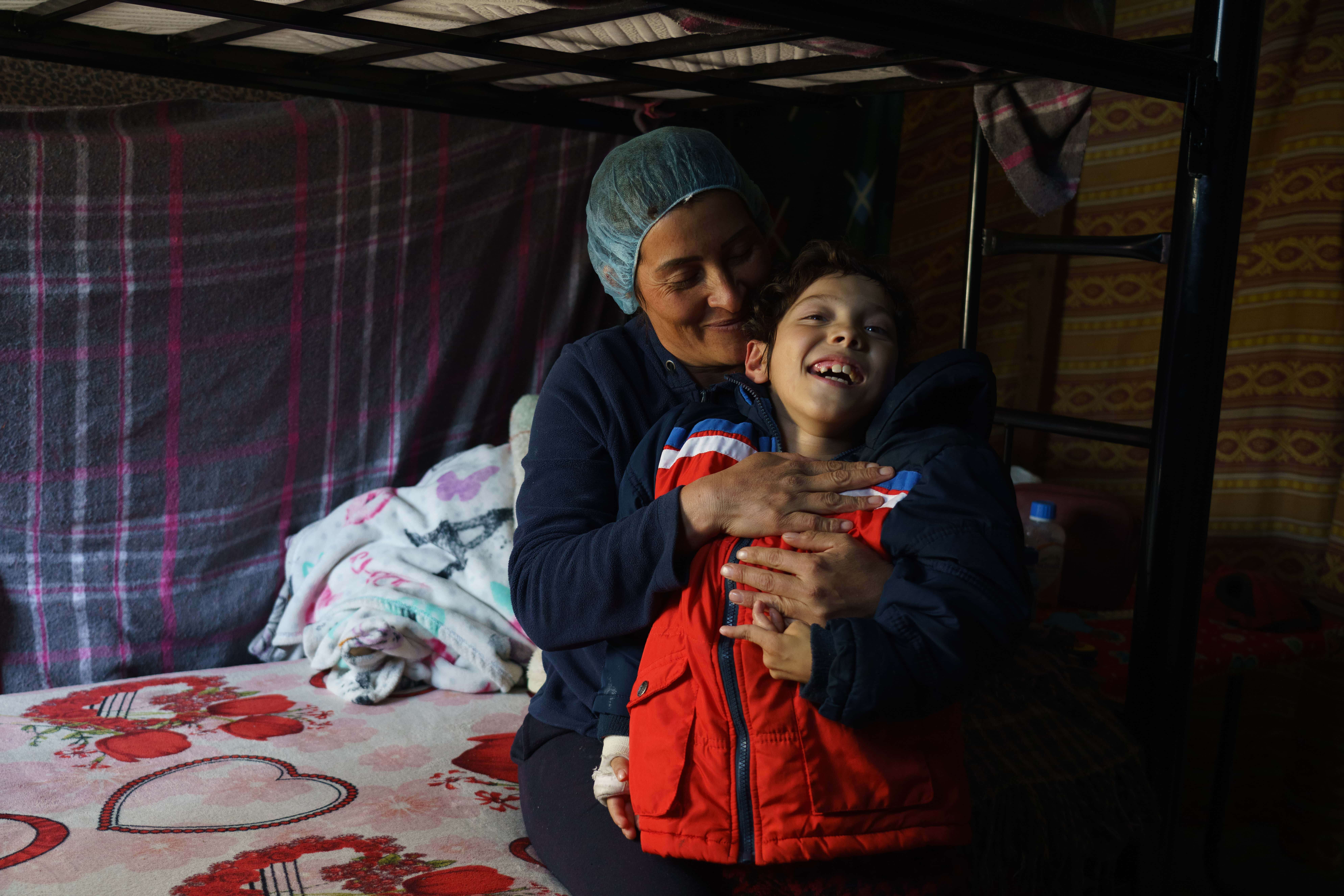 Sara*, 36, from southern Mexico, is pictured with her nine-year-old son in her bunk at Oasis del Migrante shelter in Ciudad Juárez. Sara has been waiting for an appointment via the CBP One application to seek entry into the United States with her sons, hoping to get better medical care for her nine-year-old son’s cerebral palsy. 