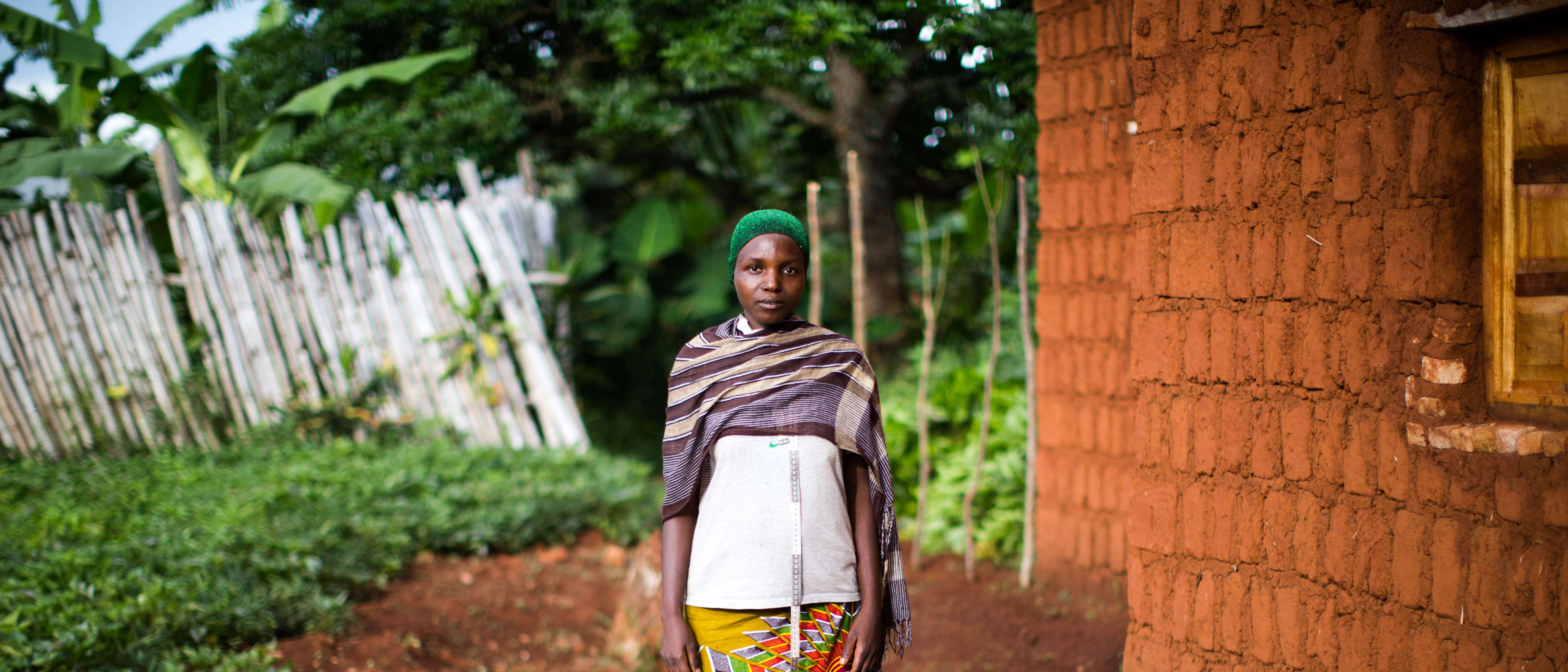A woman poses for a photo outside of a home in Burundi.