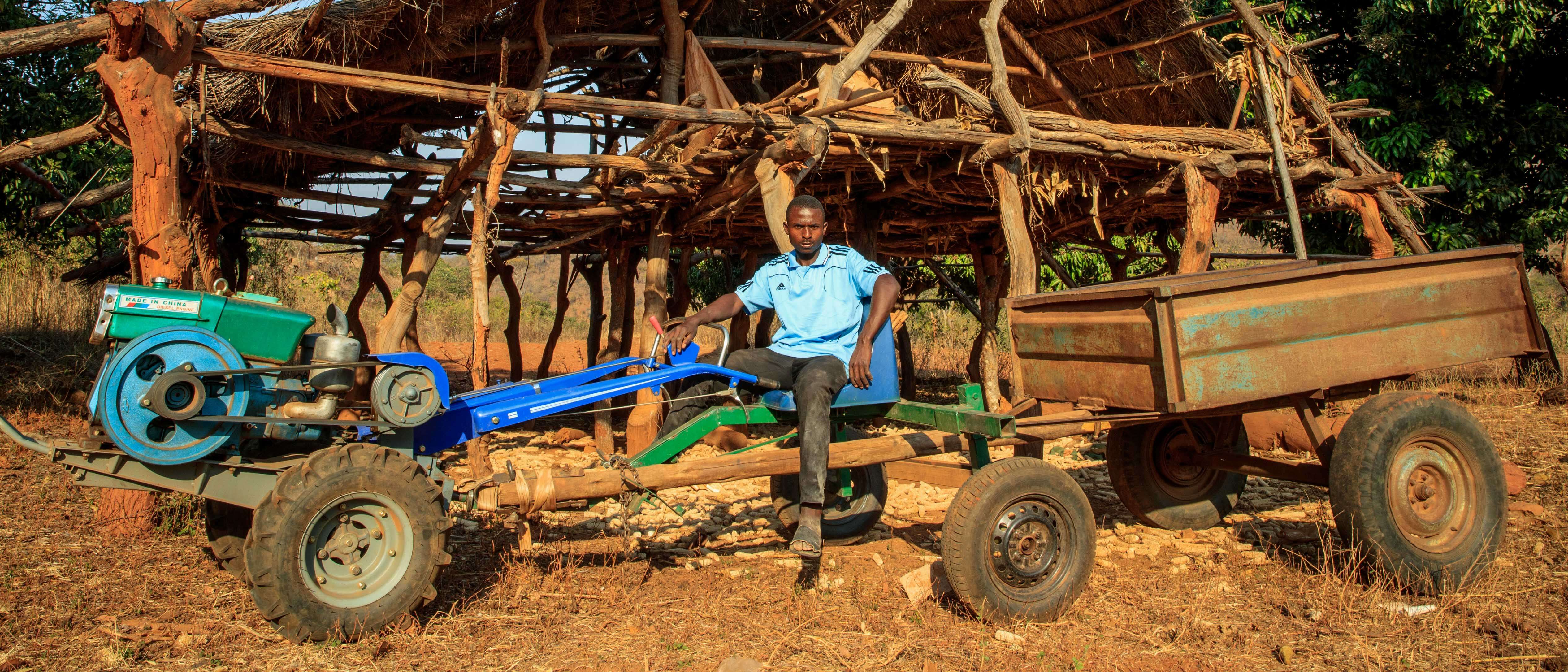 A man sits on a large tractor outside in Zimbabwe.