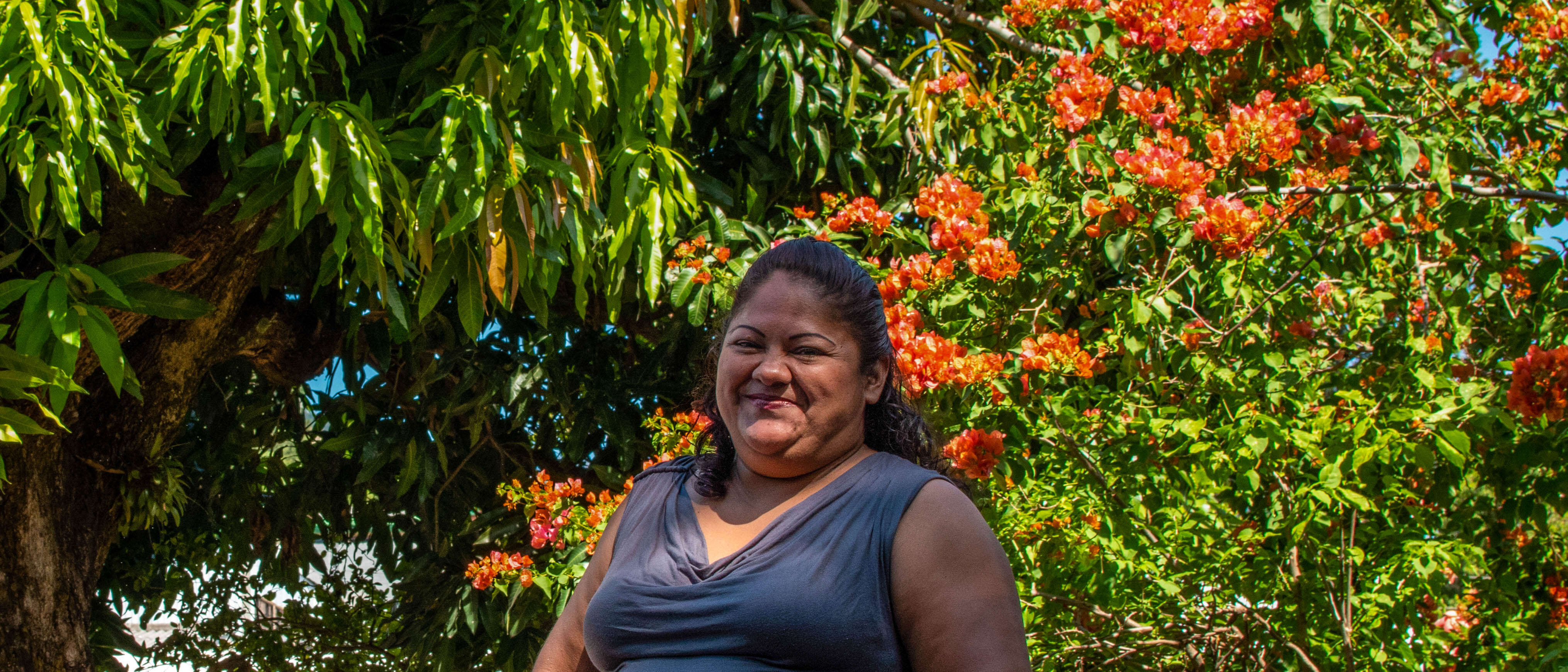 A woman stands in front of a blossoming tree and smiles for a photo.
