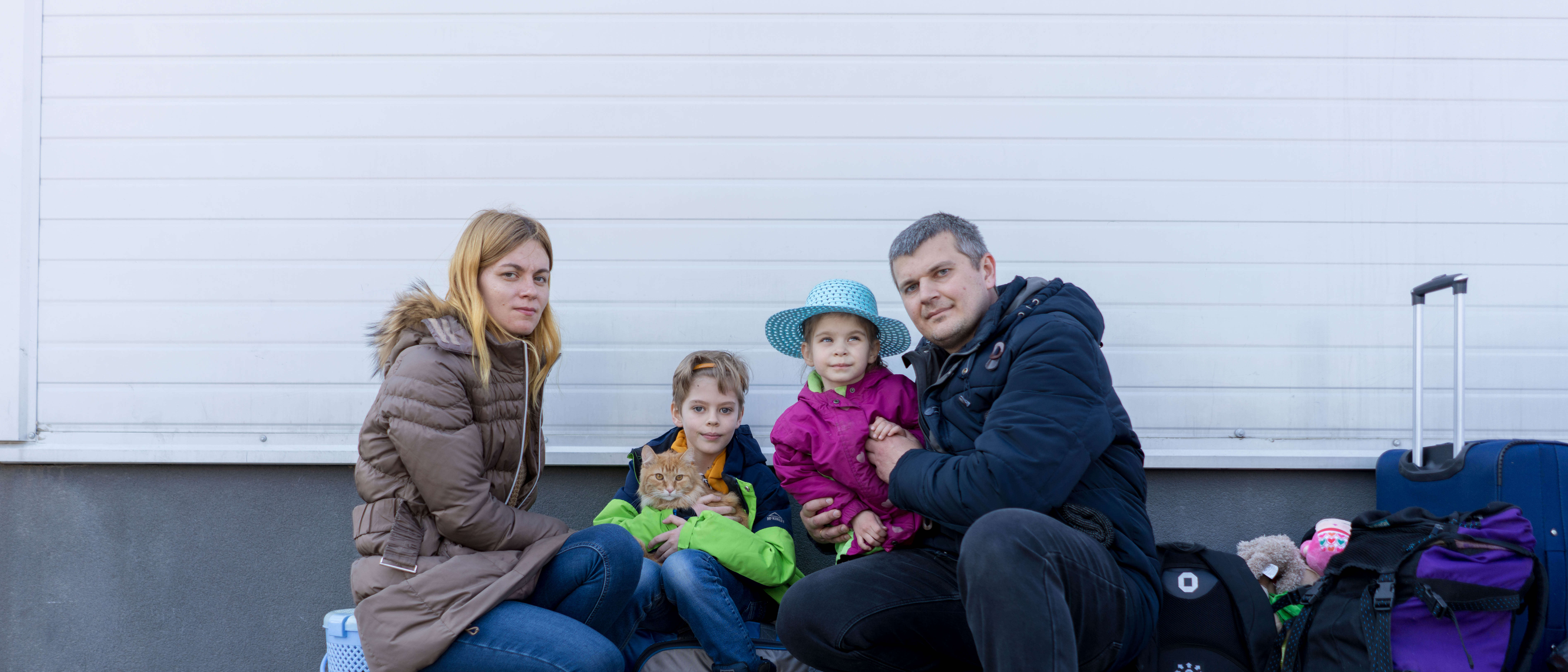 A family of four, who have recently fled war in Ukraine, pose for a picture. One of them, a young boy, holds the family's cat.