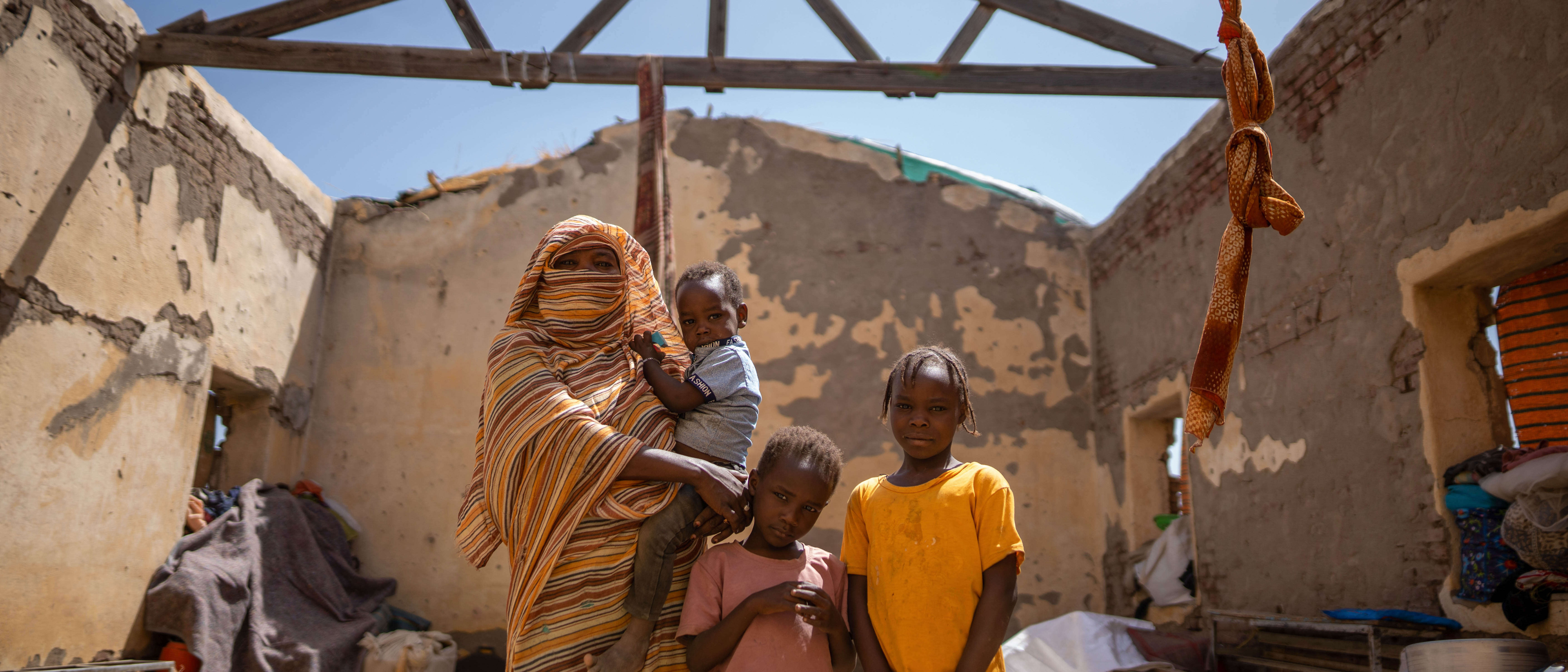A Sudanese family pose for a photo in the ruins of a building destroyed by conflict.