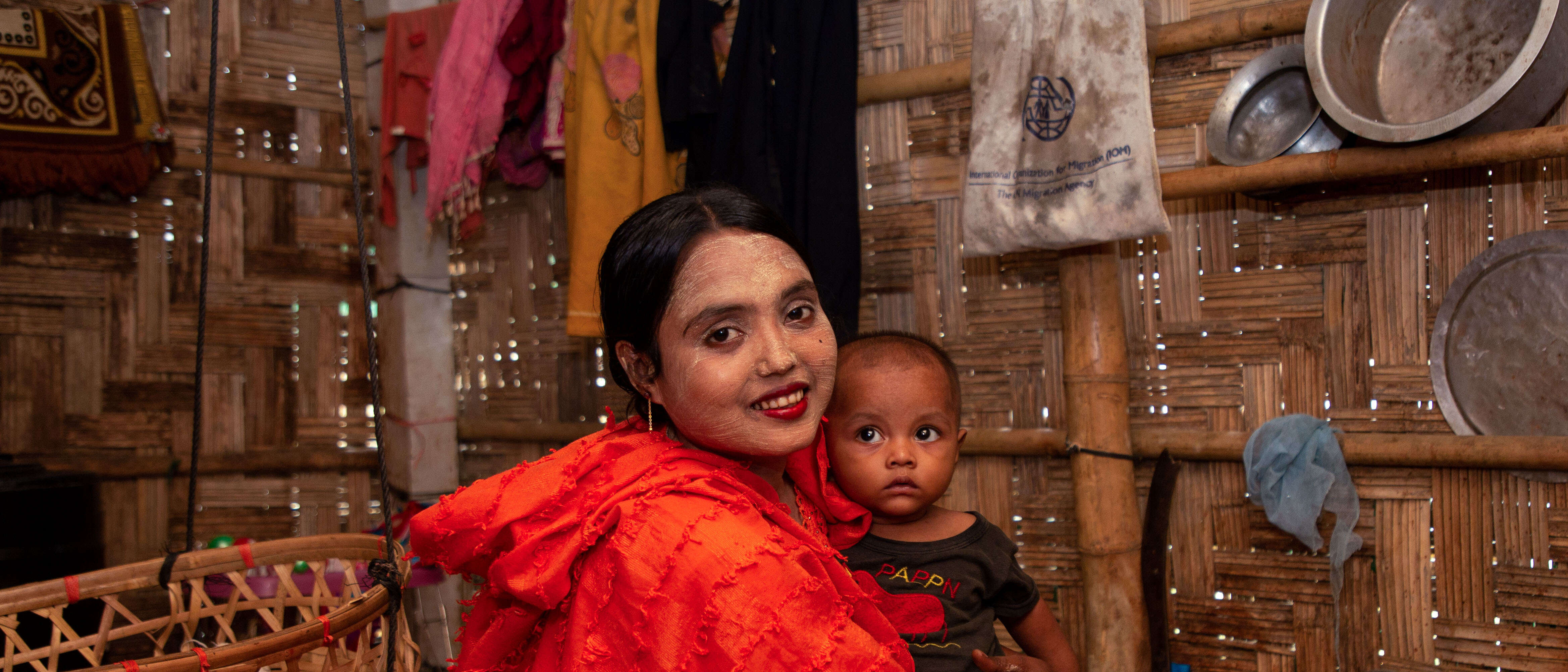 A woman in Bangladesh smiles while holding a child close to her.