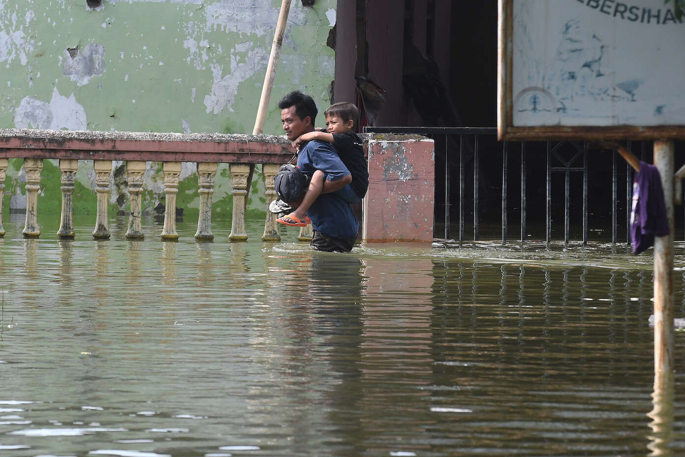 한 아버지가 홍수 속에서 자녀를 업고 탈출하고 있습니다.