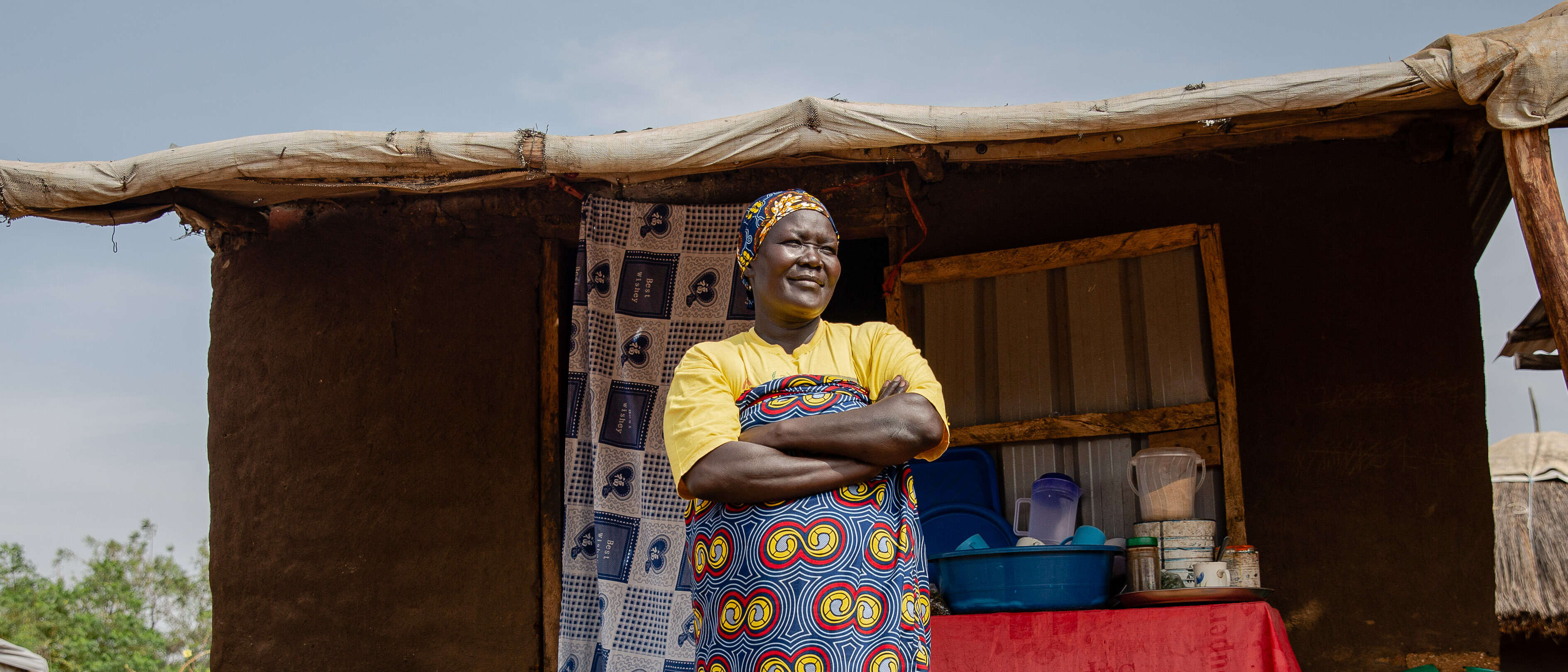 Eine Frau steht mit verschränkten Armen im Freien in Uganda.