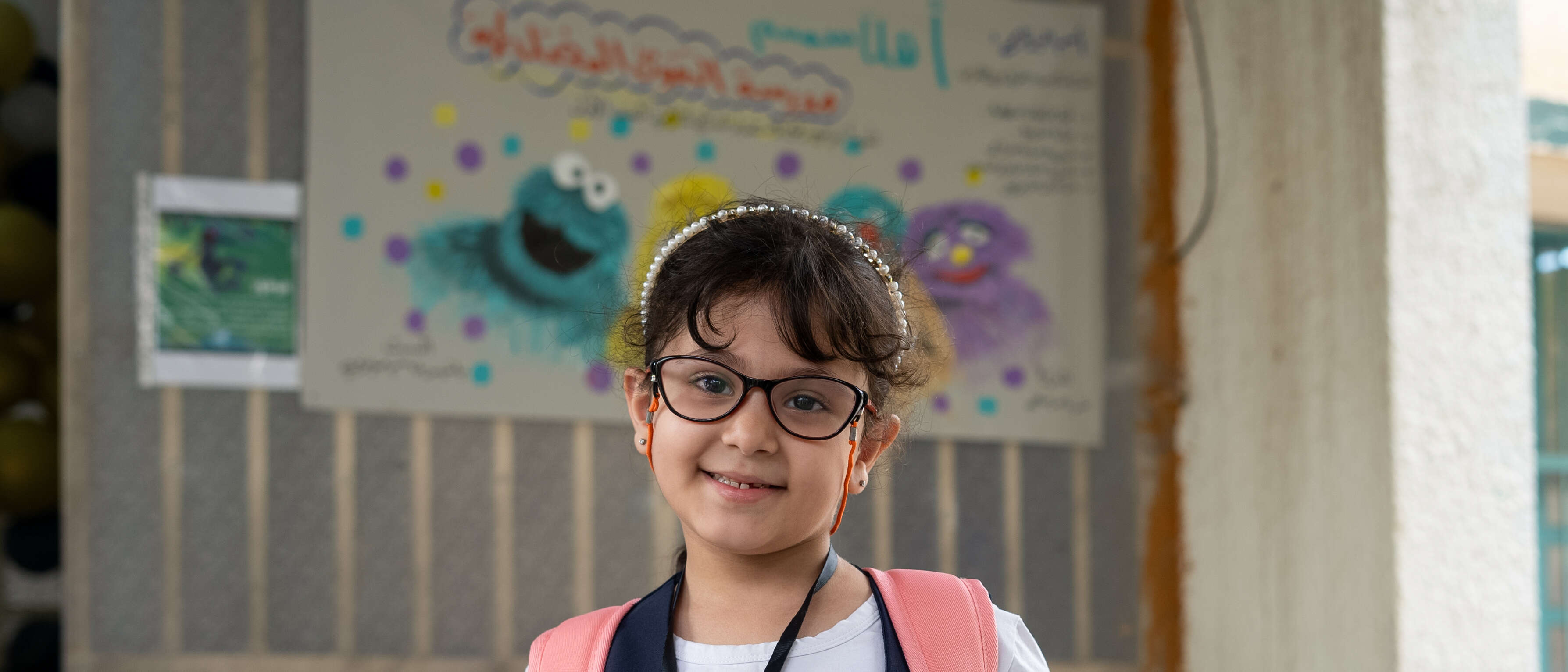 A girl in glasses poses for a photo in an IRC classroom in Iraq.