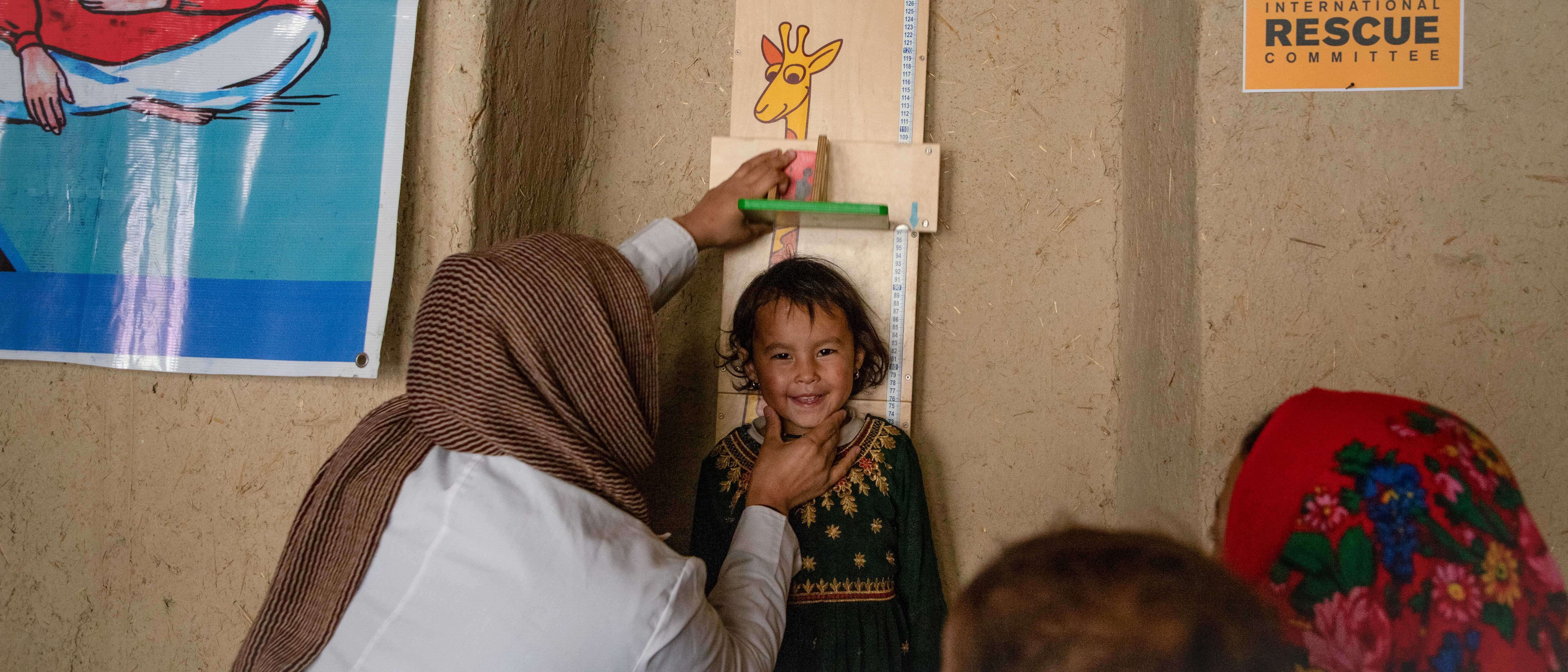 A smiling child in Afghanistan has their height measured.