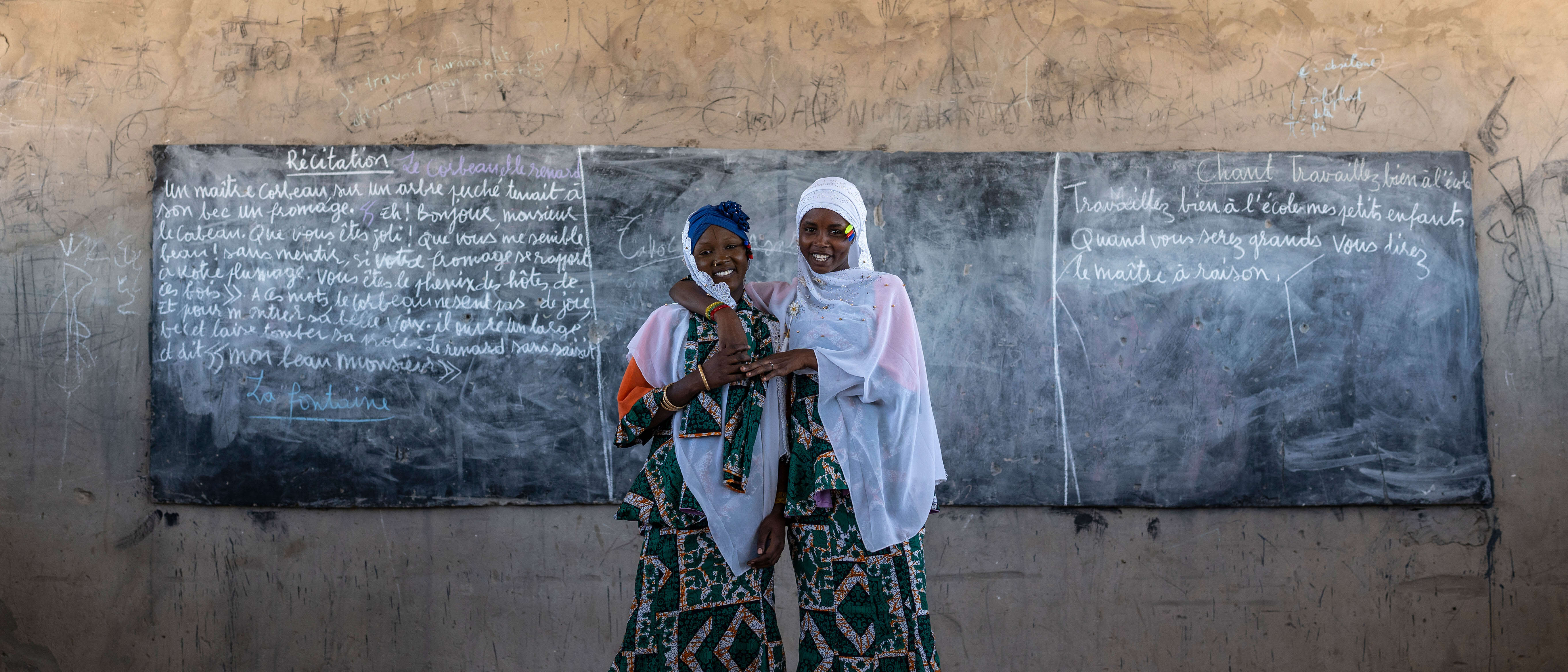 Two women stand together at the front of a classroom in Chad.