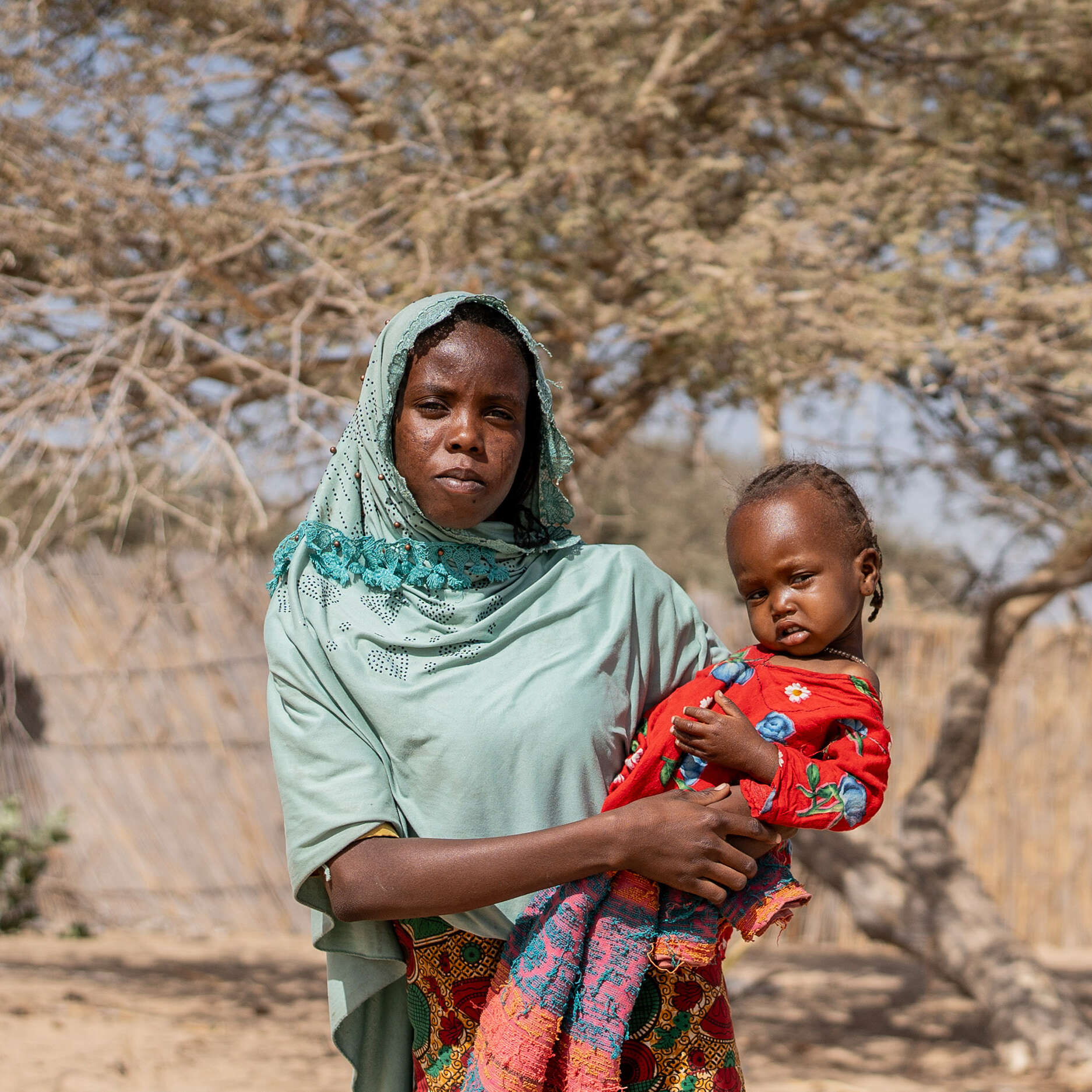 A Sudanese refugee and her one-year-old child in the dry landscape in Kafia, Chad, where IRC medical staff tested her daughter for malnutrition.