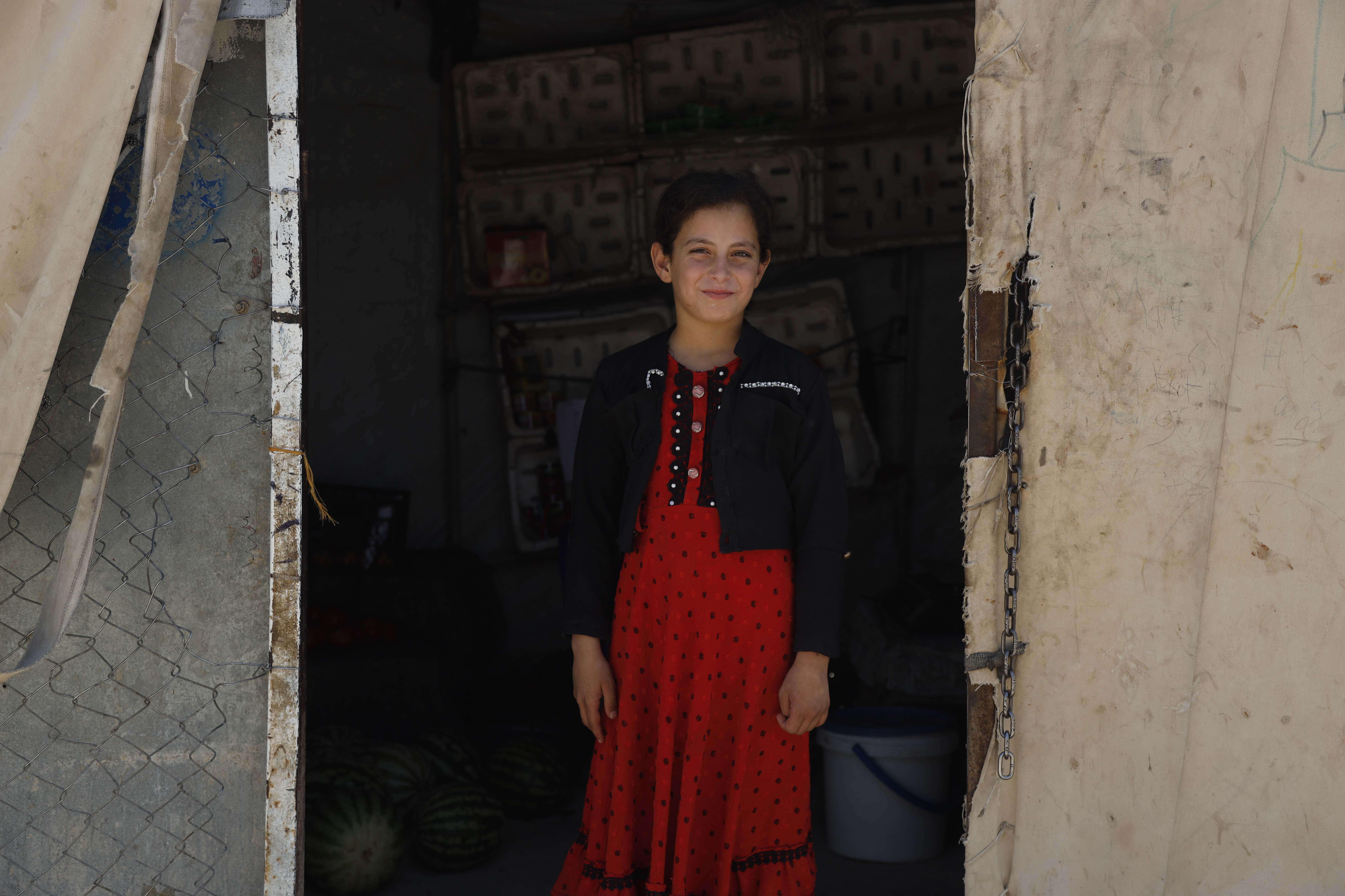 A girl stands in the middle of a doorway in Syria.