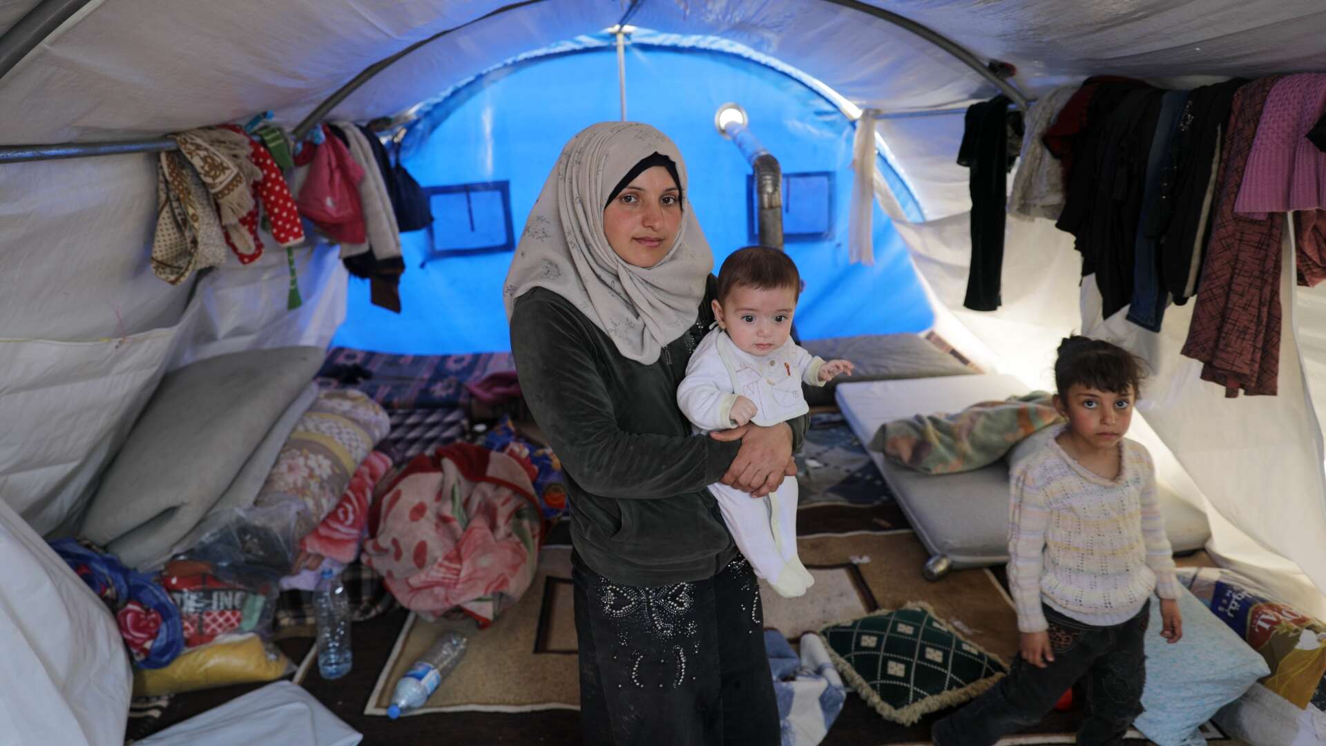 A family in Syria poses for a photo in their makeshift shelter in a refugee camp.