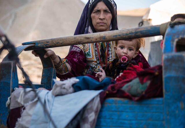 En mamma vaggar sitt sjuka barn i ett läger i det afghanska distriktet Muqur.