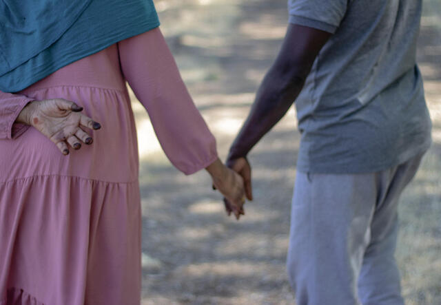 Hawaa and Yousef walk holding hands through the farm fields in Salt Lake City.