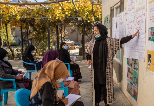 A women stands in front of others lecturing them on how to identify and treat malnutrition.