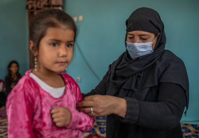 A woman holds a girls arm and screens her for malnutrition in Afghanistan.