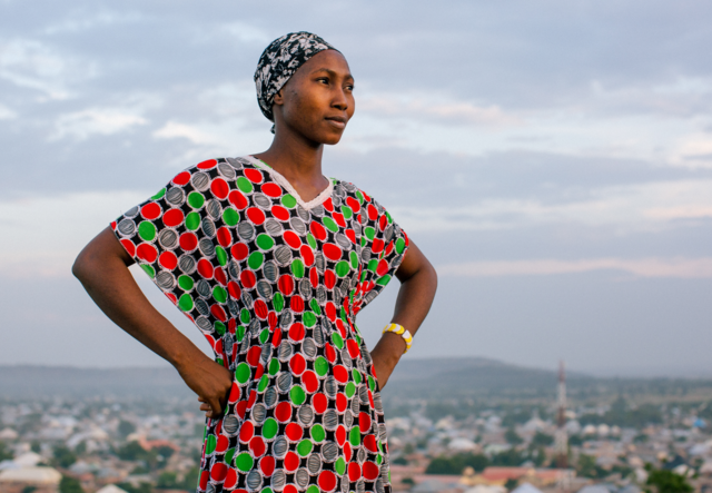 Lydia poses for a portrait on a hill above a city.