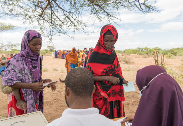 Waxyo Ali (left) and Asay Kurba are seen receiving cash from IRC staff members.