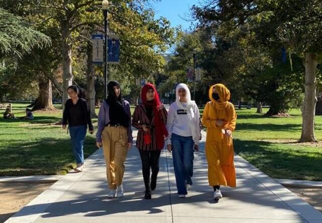 4 refugee high school youth walk on treelined campus sidewalk together