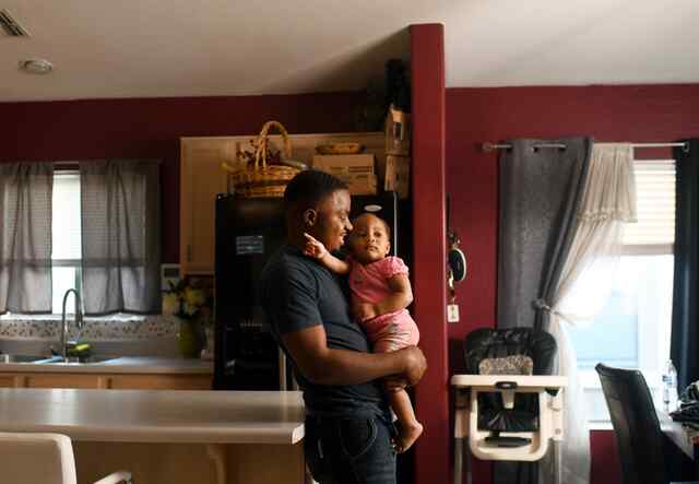 애리조나주 피닉스에 있는 집에서 어린 딸을 안고 있는 로버트.