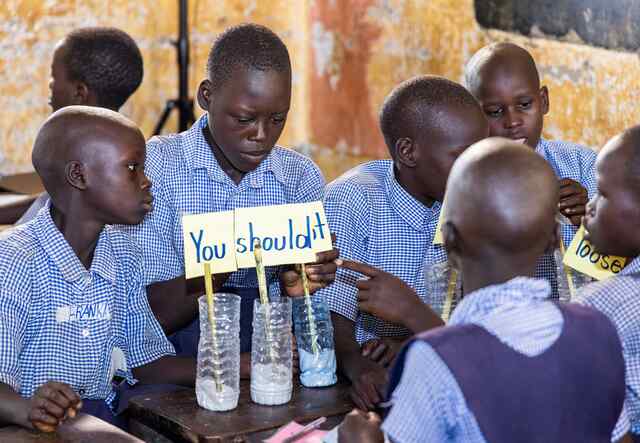 A group of students in Kitgum, Uganda attend a PlayMatters session. The students are practicing their spelling conjugations together.