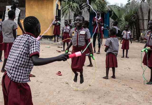 Children in Nyal laugh as they skip rope together in the front-yard of an IRC Learning Center.
