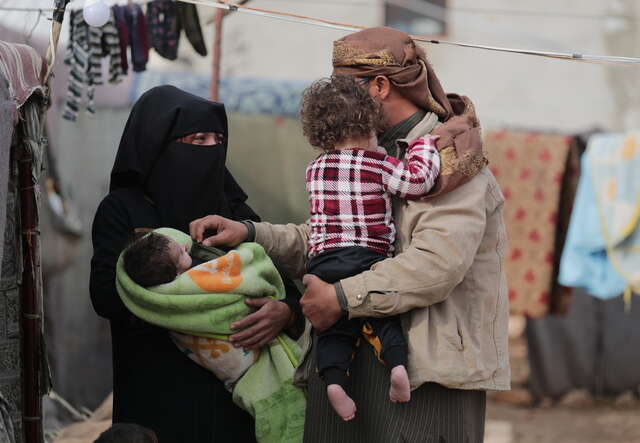 Abeer and her husband holding two of their children.