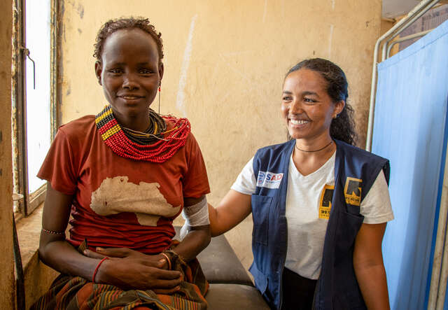 한 국제구조위원회 고객이 에티오피아의 보건 및 영양 담당자와 나란히 앉아 미소를 나누고 있습니다.