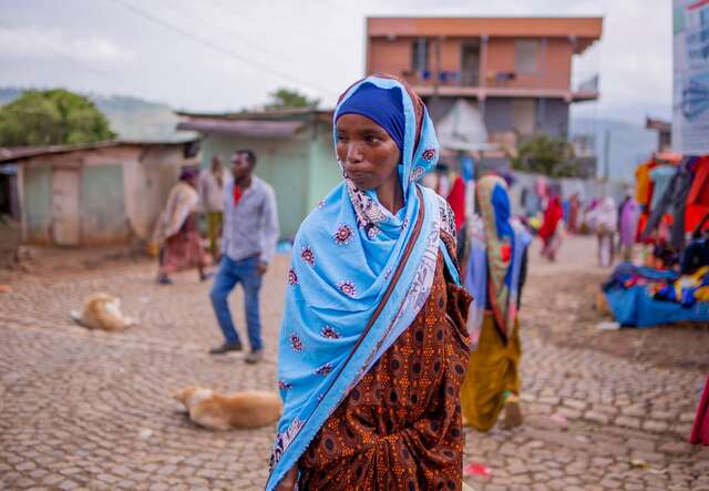 파란색 머리 스카프를 두른 한 여성이 에티오피아 데데르의 시장을 걷고 있습니다.