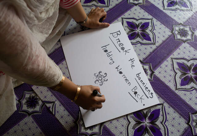 Eine Frau schreibt Slogans für die Geschlechtergleichstellung auf ein Plakat. 