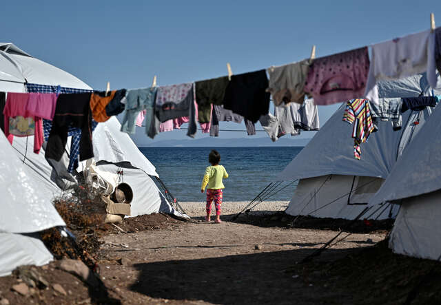 En liten flicka går bland tälten på flyktinglägret i Lesbos, Grekland.