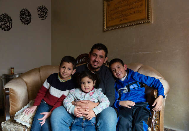 Huthaifa, 32, second right, sits with his three children, Bilal, 8, right, Misk, 3, centre, and Omar, 4, on the couch at his apartment.