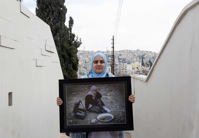 Hamida, 26, holds one of her framed photographs as she poses for a portrait.