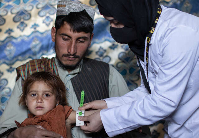 En pappa i Afghanistan med sitt barn i famnen, som blir undersökt av RESCUE:s hälsoteam.