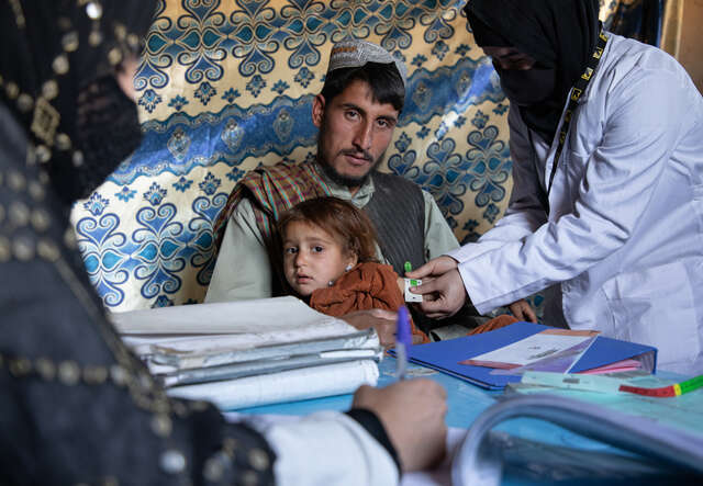 En pappa i Afghanistan med sitt barn i famnen, som blir undersökt av RESCUE:s hälsoteam.