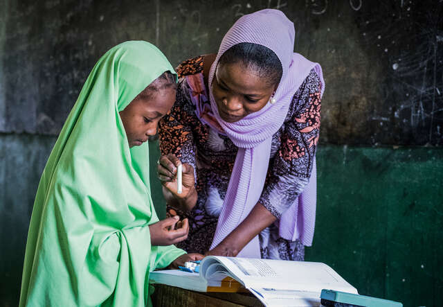 나이지리아의 한 국제구조위원회 안전한 치유 교실에서 한 선생님이 학생을 1:1로 수업을 진행하고 있습니다.
