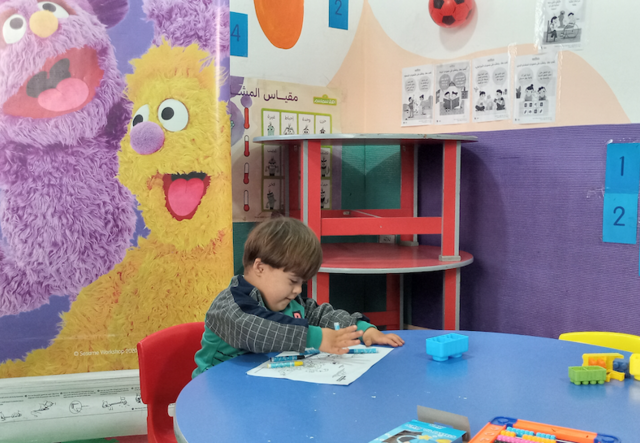 한 어린이가 아할란 심심 프로그램 교실에서 색칠에 집중하고 있습니다.