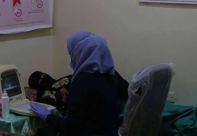 A nurse performs a prenatal examination on a woman at a health clinic.