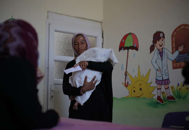 A mother holds her child while speaking to a staff member at the IRC's health care centre.
