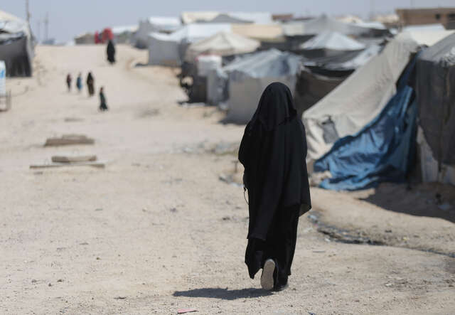 Ebtisam walks down a road in a refugee camp.