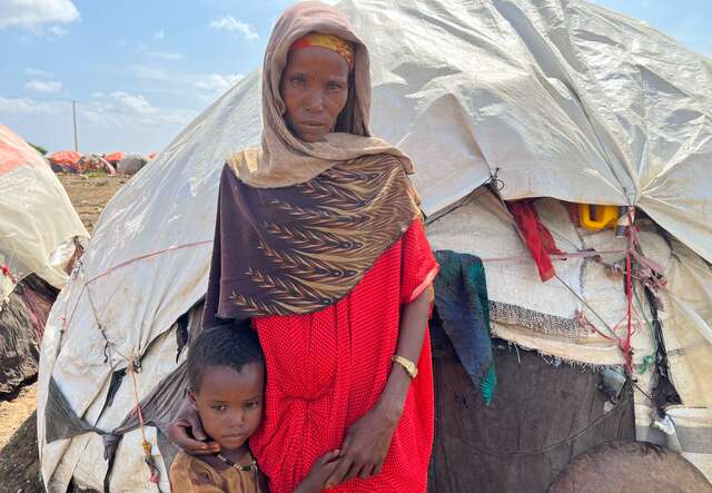 A mother stands next to her child outside their makeshift shelter in Somalia.