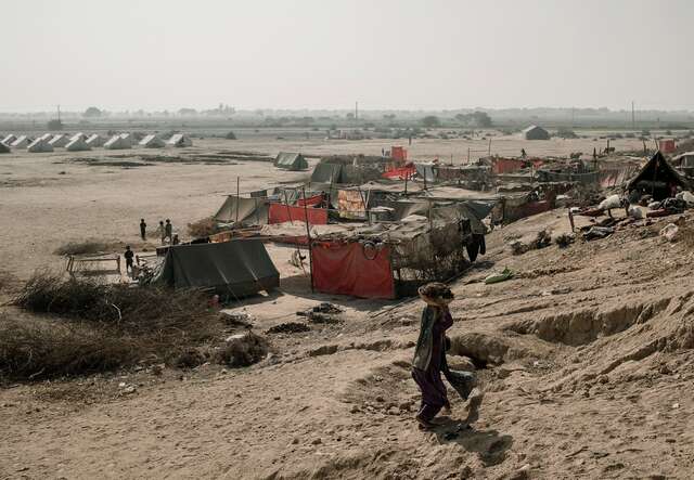 A person walks, with their back turned to the camera, through a camp for displaced people in Pakistan.