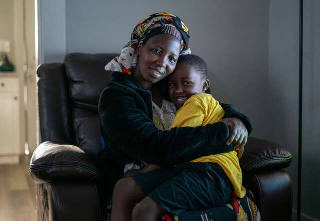 Bonfils mother, Nyabeza Nyabigazi, sits with her son, hugging him.