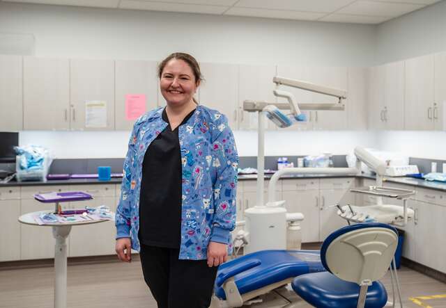 Yuliia, 39, stands in medical scrubs at the Grossmont Health Occupations Center, where she works as a general assistant.