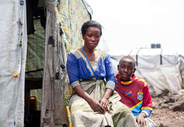 En mamma och barn sitter utanför ett tält i ett flyktingläger i Goma, Kongo-Kinshasa där konflikten drivit miljontals människor på flykt.