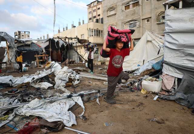 A boy carries a blanket through a destroyed neighborhood in Gaza.