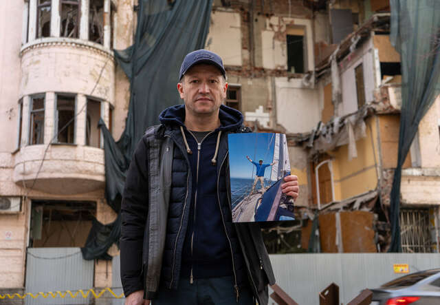 Andrii holds a photo of him on a yacht during his travels before the full-scale war erupted. 