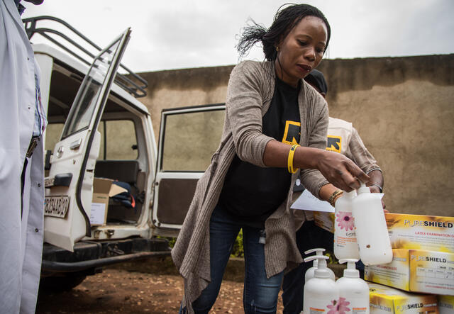 Dr. Sylvie Musema Ngimba of the IRC unloads personal protective eqipment and sanitizer from a 4-wheel-drive vehicle.
