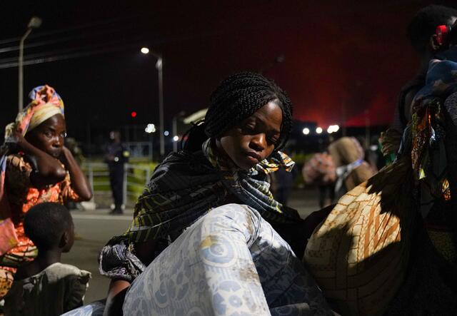 고마 근처에서 니라공고 화산이 폭발한 후 사람들이 르완다로 대피하는 동안 한 젊은 여성이 매트리스와 기타 소지품을 운반하고 있습니다.