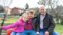 Oleksandr sits on a bench with his two grandchildren.